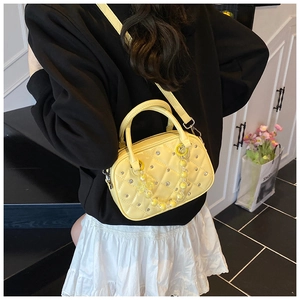 Close-up of quilted yellow mini bowling bag with sparkling rhinestones and floral charm