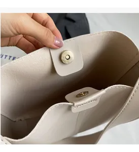 Détail du sac seau beige clair montrant le fermoir magnétique et doré poli