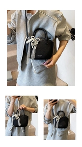 Detail of black pebbled leather crossbody bag with pearl lace bow and logo print