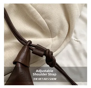Detail shot of the adjustable knotted shoulder strap on a brown soft leather crossbody bag