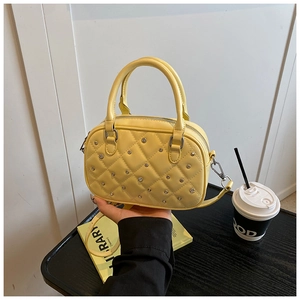 Macro view of bright yellow quilted Boston bag with silver studs and smooth PU leather texture