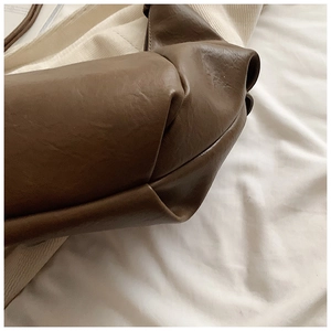 Detail shot of the soft dark brown faux leather texture and side stitching on the slouchy bag