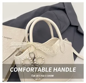 Detail of white lychee textured handbag with lace bow and elegant pearl ornament