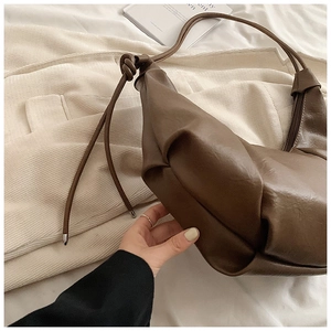 Detail of soft brown leather slouchy dumpling bag with knotted strap and metal tip accents