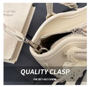 Detailed macro view of silver metal clasp and zipper on a cream textured leather handbag
