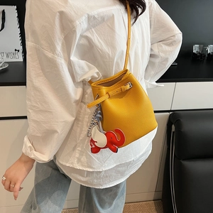 Gelbe Eimer-Tasche aus Litschileder mit Elefantenanhänger am weißen Hemdmodell