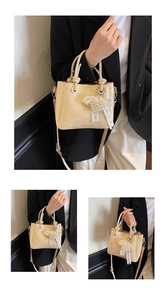 Detail of cream bucket bag featuring heart pearl lace charm and logo textured leather