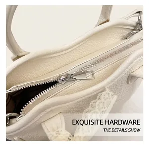 Detailed macro view of white lychee grain leather handbag with silver zipper and lace trim