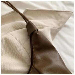 Detailed close-up of brown textured leather and cream corduroy fabric on a soft shoulder bag