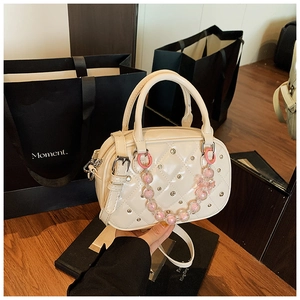 Detail of a quilted beige Boston bag featuring diamond stitching and a pearl beaded chain