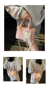 Detailed view of pink pleated handbag with lace bow and pearl heart charm accents