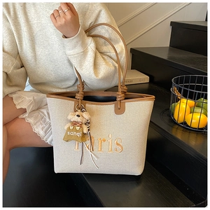 Detail of cream canvas tote bag with brown leather handles and Paris embroidery