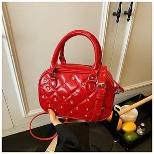 Detail of red quilted mini Boston bag with silver studs and adjustable shoulder strap