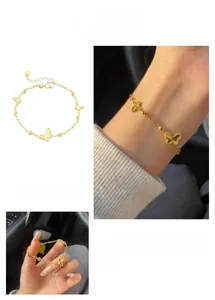 Gros plan d'un bracelet papillon doré avec breloques ajourées et petites perles