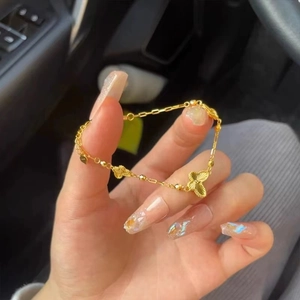 Élégant bracelet papillon doré avec chaîne fine et pendentifs porté à la main