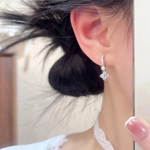 Elegant silver four-leaf clover earrings with pearl and cubic zirconia on a model