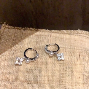 Detail of silver drop earrings featuring pearl and four-leaf flower zirconia charms