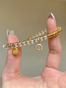 Close-up of double-layer white crystal bracelet with gold 'Shun' charm and pavé pendant