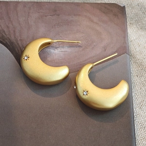 Matte gold crescent earrings with sparkling star detailing shown from a 45-degree angle