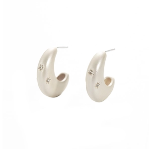 Macro detail of silver crescent earrings featuring matte finish and starburst zircon stones