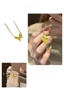 Detail of gold brushed metal butterfly and floral bracelet with asymmetrical design