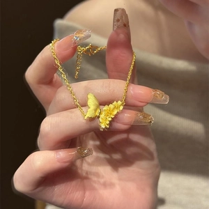 Golden brushed butterfly and flower bracelet with twisted chain in warm sunlight