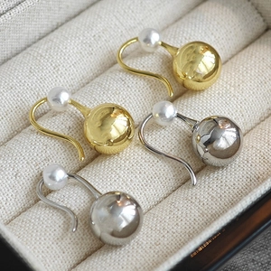Minimalist pearl drop earrings in gold and silver finish on a beige velvet jewelry box