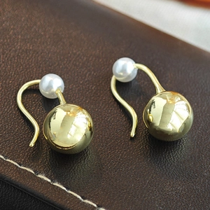 Elegant gold drop earrings with white pearls on a textured dark leather background