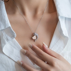 Detail of dolphin heart necklace with zircons and pink gemstone on a model