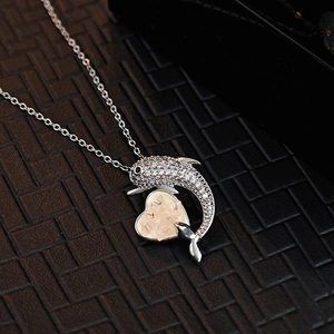 Elegant silver dolphin necklace with a pink heart stone and zircon accents on a black pad