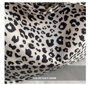 Close-up of leopard print fabric with twill texture and golden metal snap button