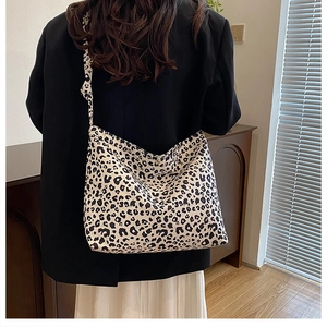 Detailed back view of model wearing a large leopard print canvas tote bag in a home setting