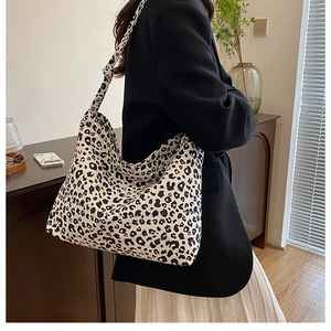 Detailed view of high-capacity leopard print hobo bag worn with black blazer and pleated skirt