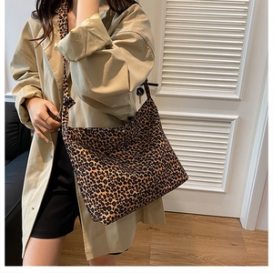 Detail of leopard print tote bag featuring metallic snap closure and wide shoulder strap