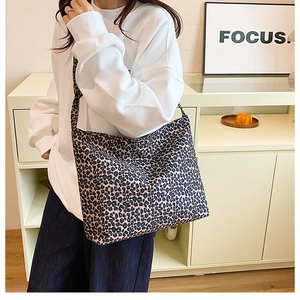 Close-up of leopard print canvas shoulder bag worn by model in a stylish interior setting