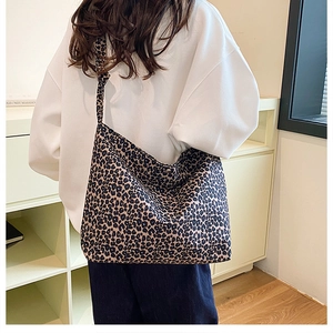 Large leopard print canvas tote bag with wide shoulder strap styled on a model