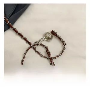 Detailed macro view of silver chain strap interwoven with brown leather and quilted metal ball