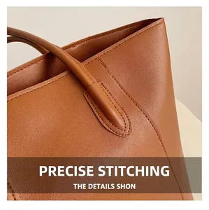Detail of precise stitching on the brown leather tote bag shoulder strap connection