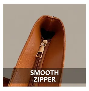 Detail of premium caramel lychee grain leather texture and smooth golden metal zipper closure