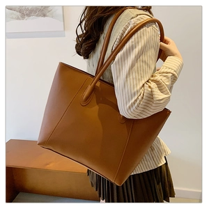 Photo lifestyle d'un grand sac cabas en similicuir marron porté par un mannequin chic