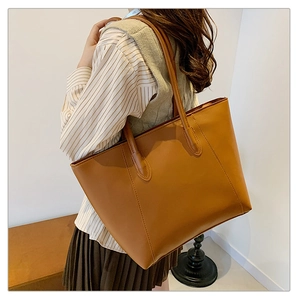 Brown leather tote bag featuring a spacious design and sleek shoulder straps on a model