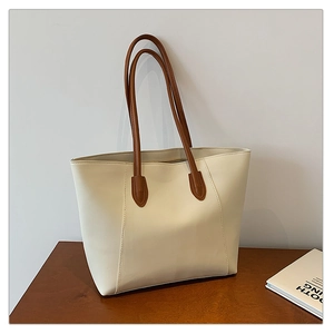Détail d'un grand sac cabas crème avec des lanières marron sur bois sombre