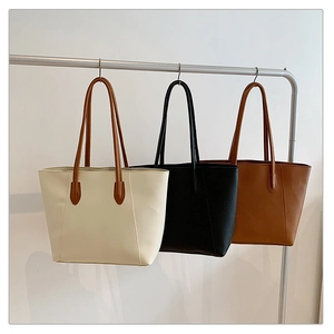 Minimalist faux leather tote bags in cream, black, and brown hanging on display