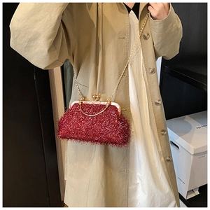 Close-up of luxury red plush shell bag with gold clasp and chain strap on a model