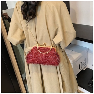 Red velvet vintage shell evening bag with golden chain handle on a beige trench coat