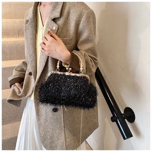 Detail of elegant black feathered evening clutch with gold chain and pearl handle strap