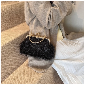 Detail of black faux fur shell bag with gold metal frame and elegant chain strap