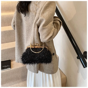 Detail of black feather shell clutch bag with gold metal frame and chain shoulder strap