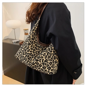 Detail of leopard print crescent bag with leather trim and brown shoulder strap