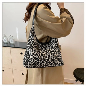 Detailed view of leopard print hobo bag with black leather straps on a khaki trench coat